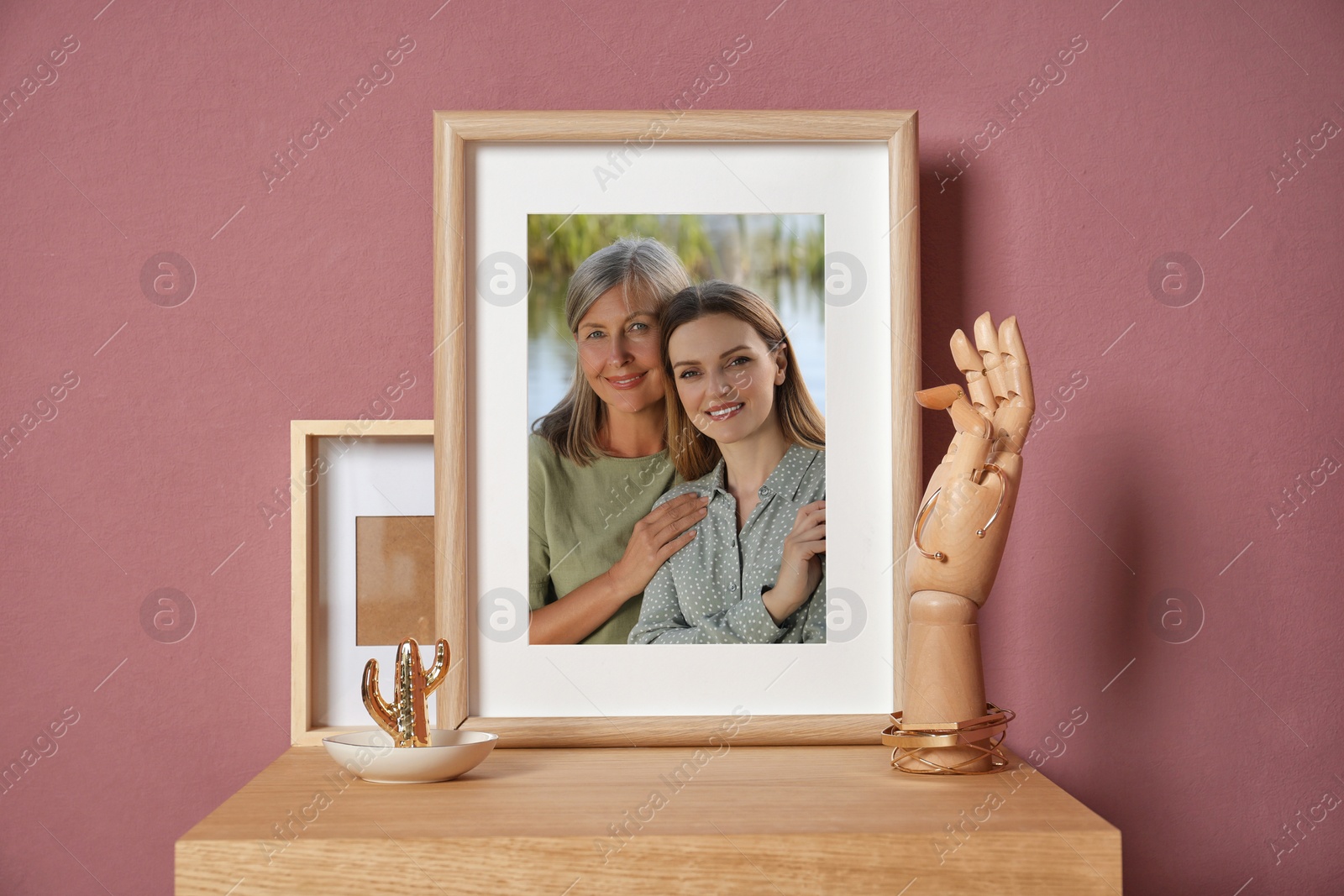 Image of Family portrait of mother and daughter in photo frame on table near color wall