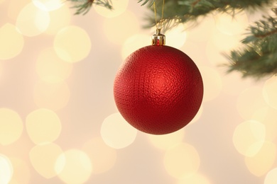 Photo of Beautiful holiday bauble hanging on Christmas tree against blurred lights, closeup