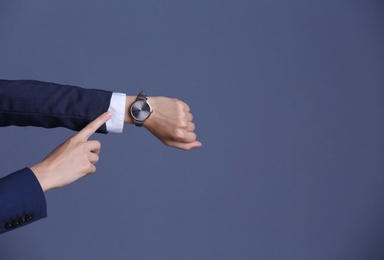 Businesswoman with wristwatch on color background. Time concept