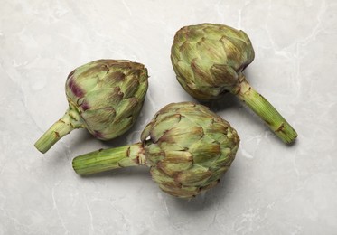 Fresh raw artichokes on grey marble table, flat lay