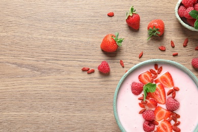 Smoothie bowl with goji berries on wooden table, flat lay. Space for text