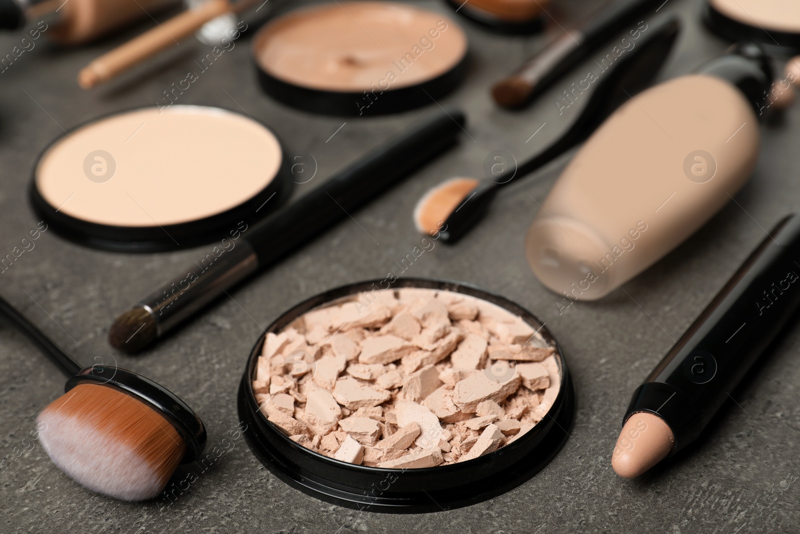 Photo of Composition with powder, skin foundation and beauty accessories on grey background