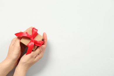 Woman holding gift box on white background, top view. Space for text