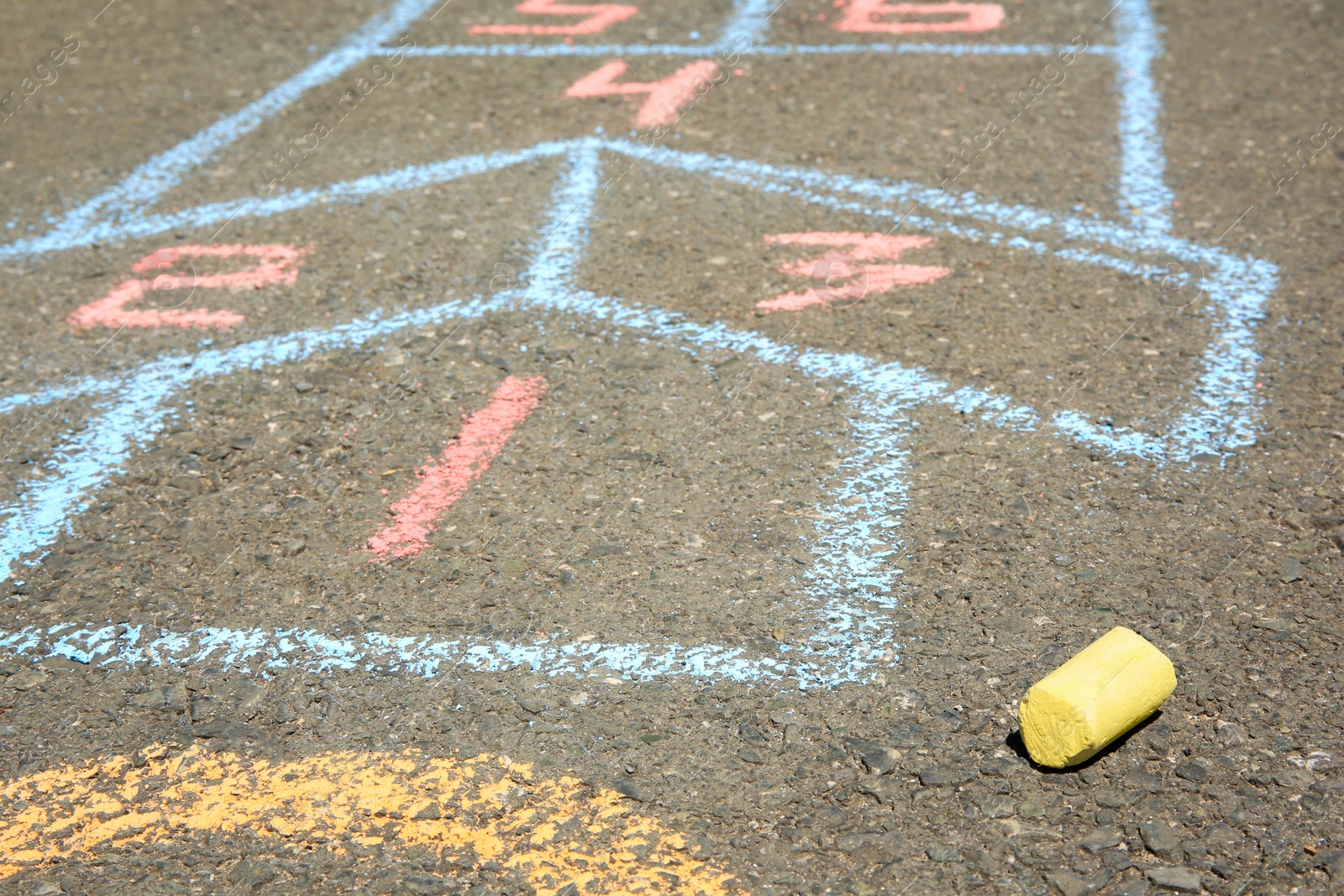 Photo of Hopscotch drawn with colorful chalk on asphalt outdoors, closeup