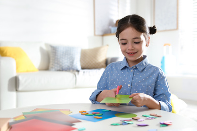 Little girl making greeting card at table indoors, space for text. Creative hobby