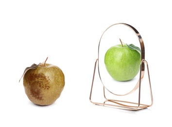 Image of Spoiled apple and mirror with reflection on white background