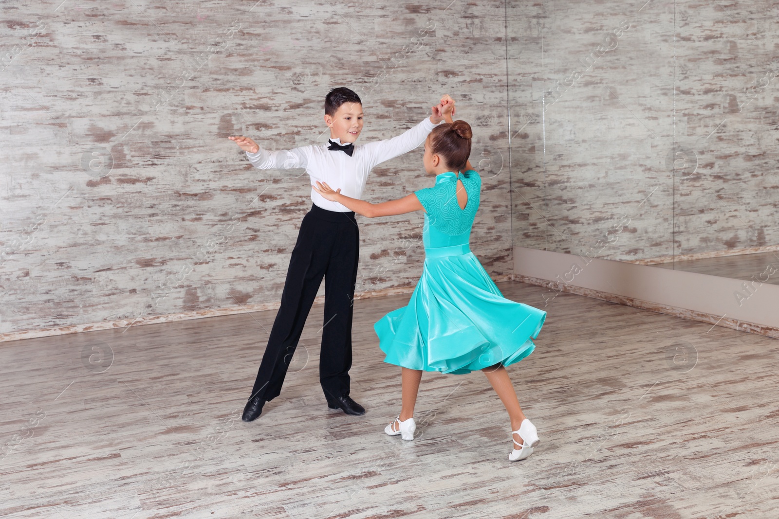 Photo of Beautifully dressed couple of kids dancing together in studio