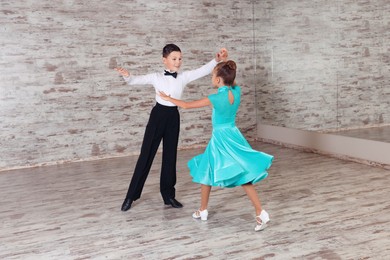 Beautifully dressed couple of kids dancing together in studio