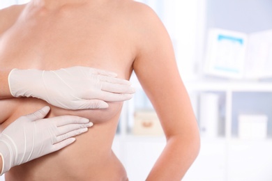 Doctor checking woman's breast at hospital, closeup