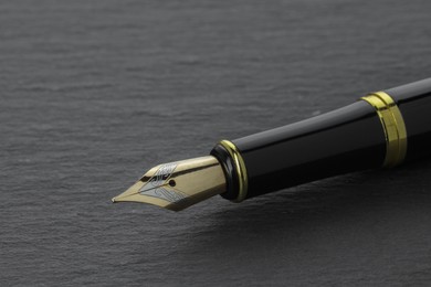 Photo of Stylish fountain pen on dark textured table, closeup