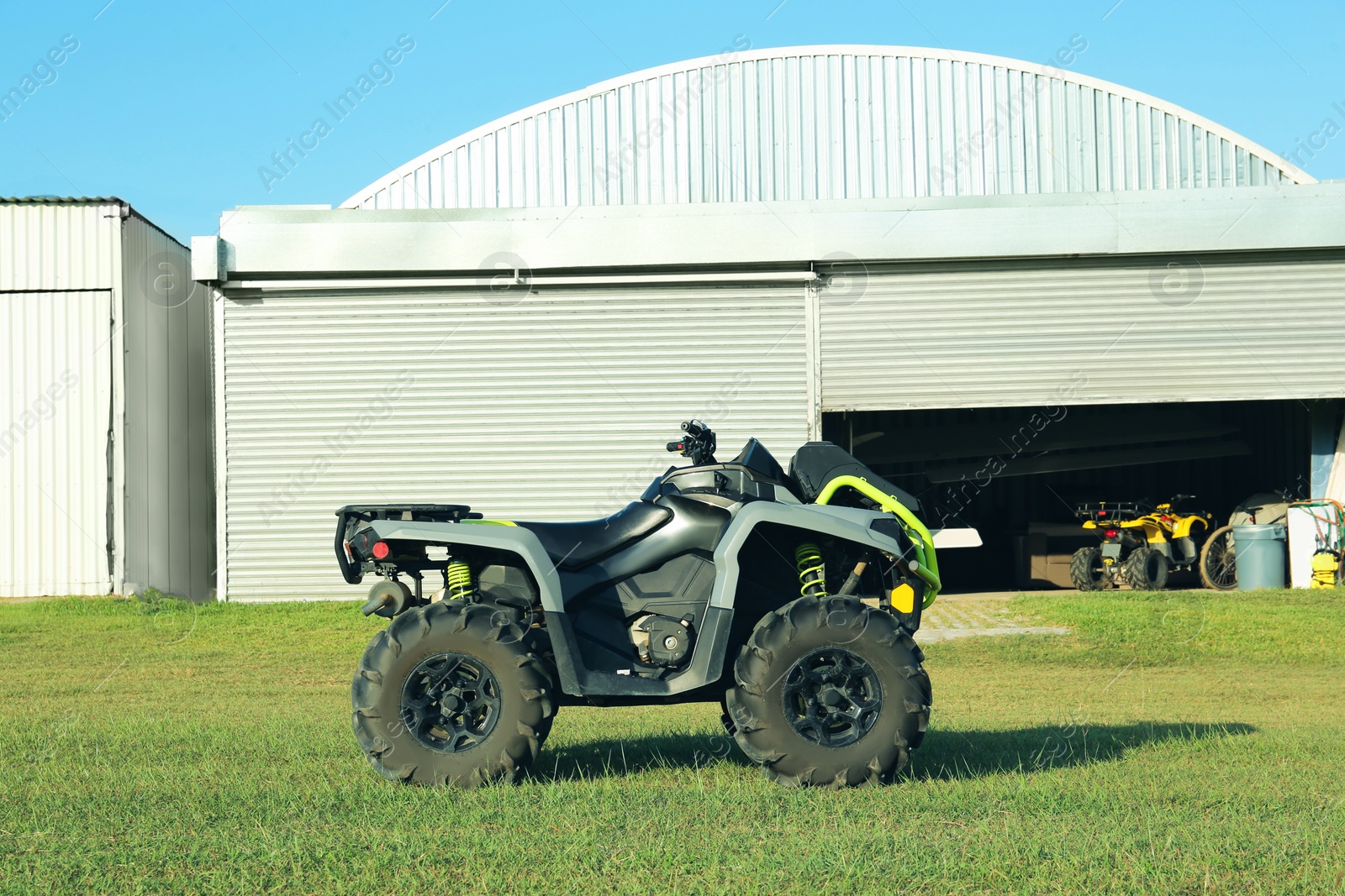 Photo of Modern quad bike in field near hangars on sunny day