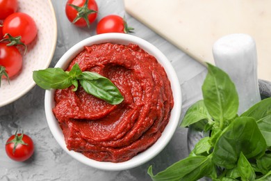 Photo of Tasty tomato paste and ingredients on light gray table, flat lay