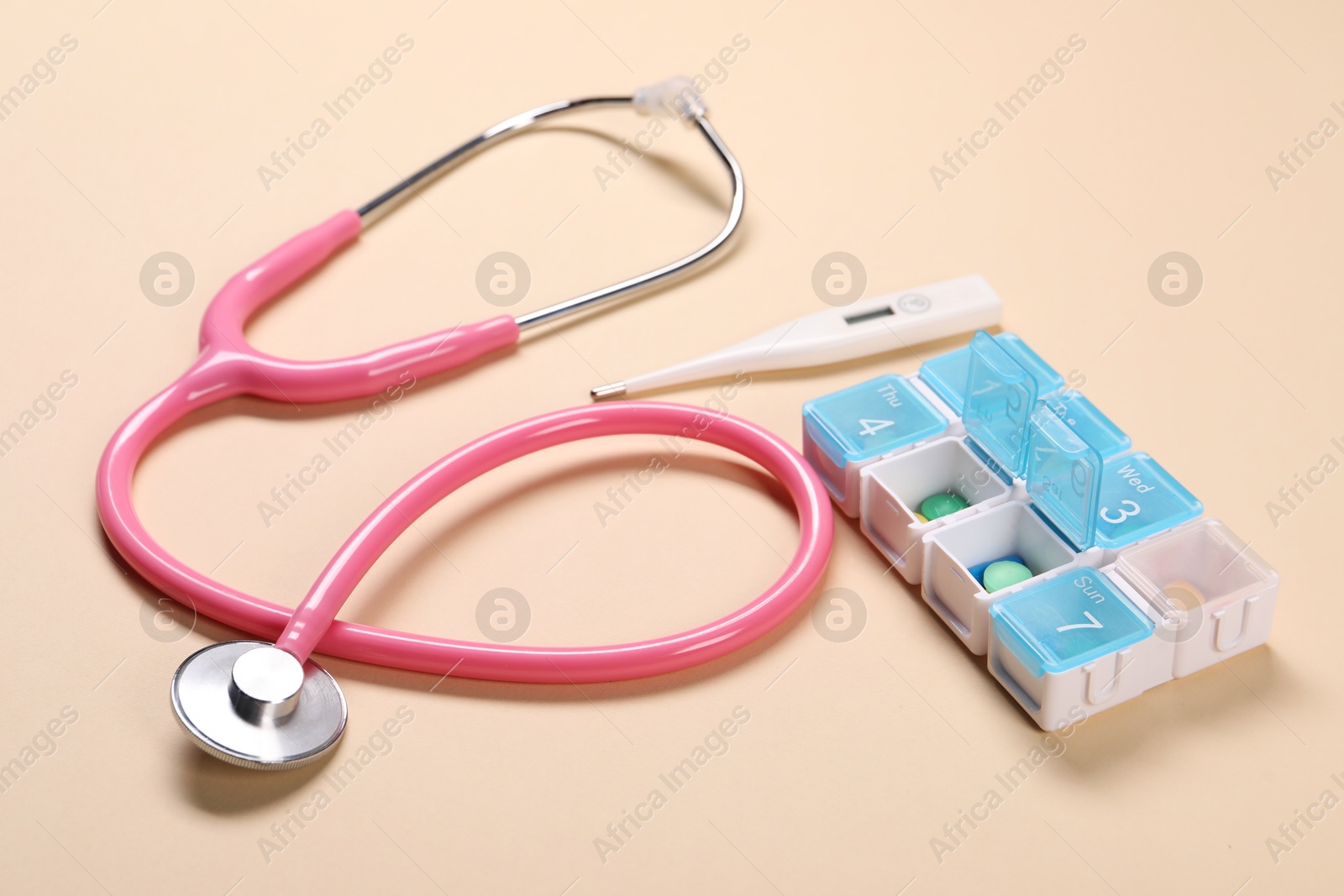 Photo of Stethoscope, thermometer and pills on beige background, closeup. Medical treatment