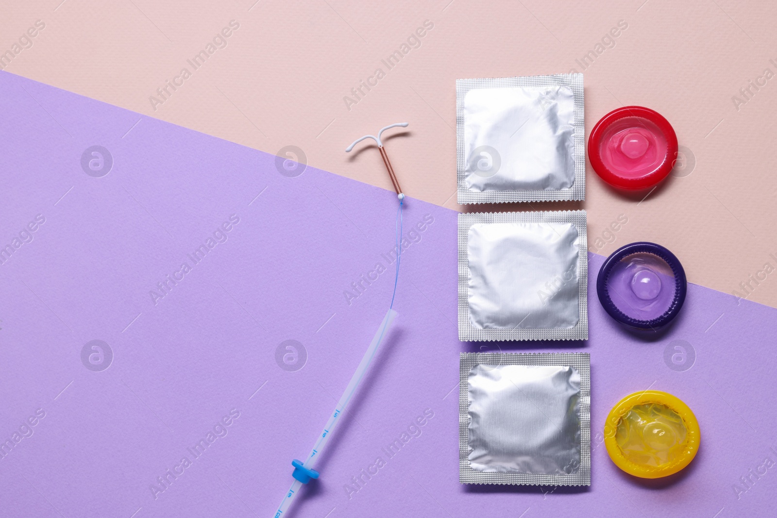 Photo of Condoms and intrauterine device on color background, flat lay and space for text. Choosing contraceptive method