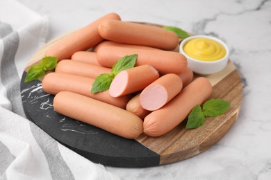 Photo of Delicious boiled sausages, sauce and basil on white marble table, closeup