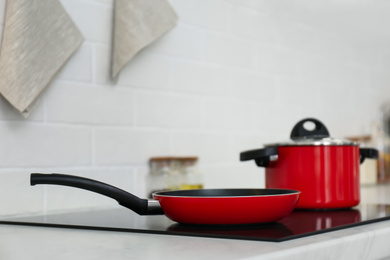 Red pot and frying pan on stove in kitchen