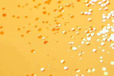 Photo of Shiny bright orange glitter on yellow background