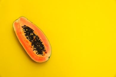 Photo of Fresh juicy halved papaya on yellow background, top view. Space for text