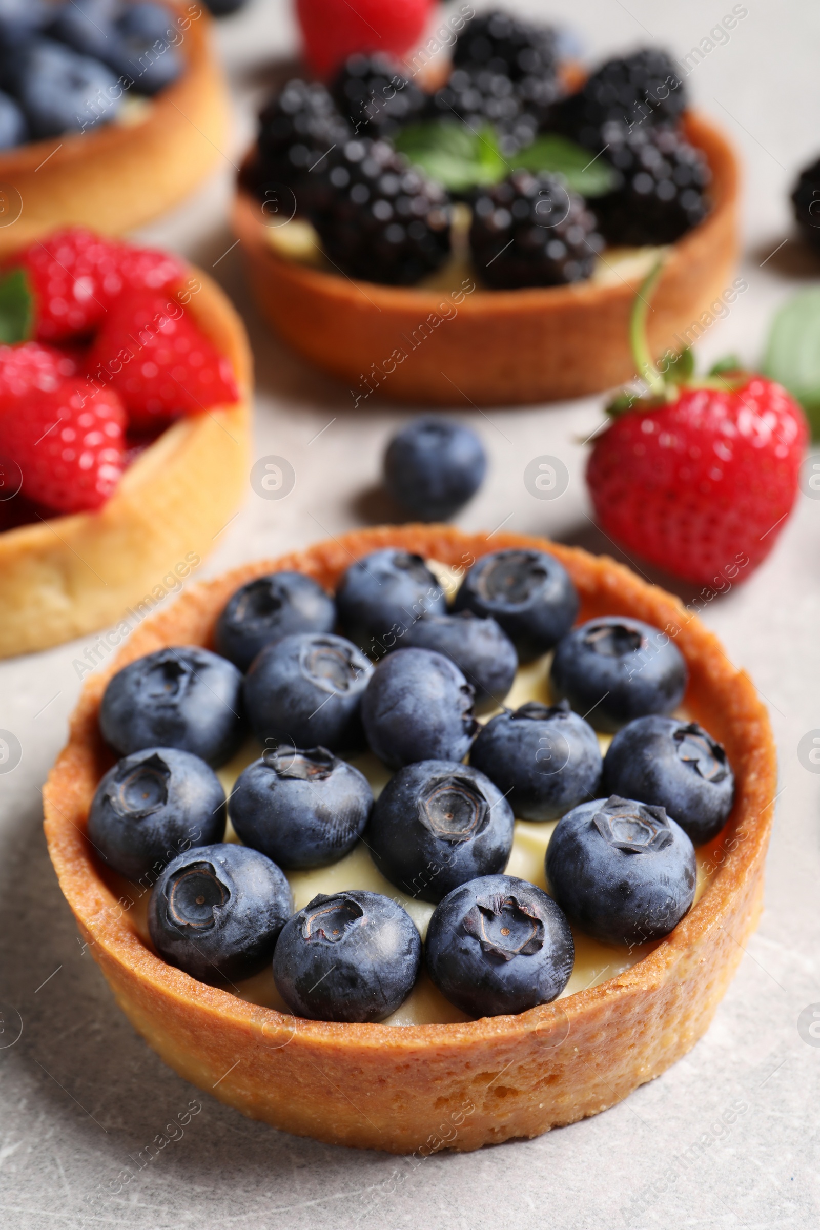 Photo of Tartlet with fresh blueberries on light grey table, closeup. Delicious dessert