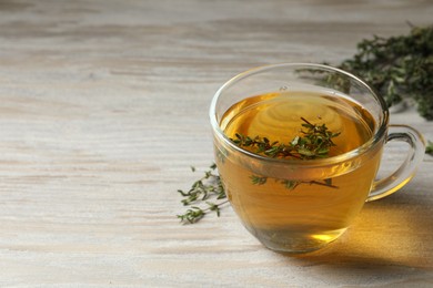 Photo of Cup of fresh thyme tea on wooden table, space for text