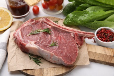 Photo of Raw meat, rosemary and products on white table, closeup