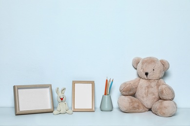 Photo of Composition with soft toys and photo frames on white background. Child room interior decor