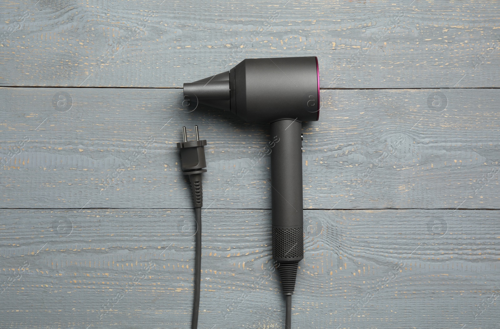 Photo of Hair dryer on wooden table, top view. Professional hairdresser tool