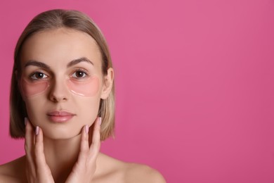 Beautiful young woman with under eye patches on pink background, space for text