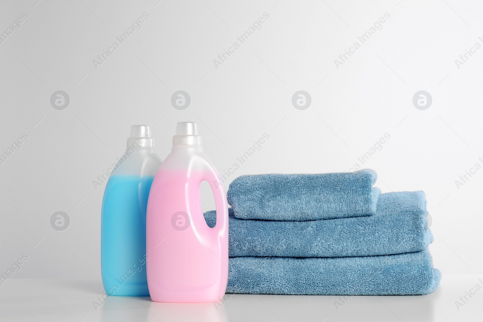 Photo of Detergents and clean towels on white background. Laundry day