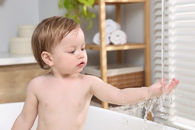 Cute little child bathing in tub at home