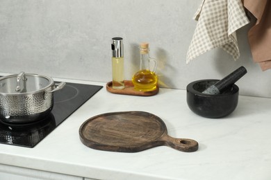 Photo of Wooden cutting board and other cooking utensils on white countertop in kitchen