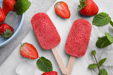 Photo of Tasty strawberry ice pops on grey table, flat lay. Fruit popsicle