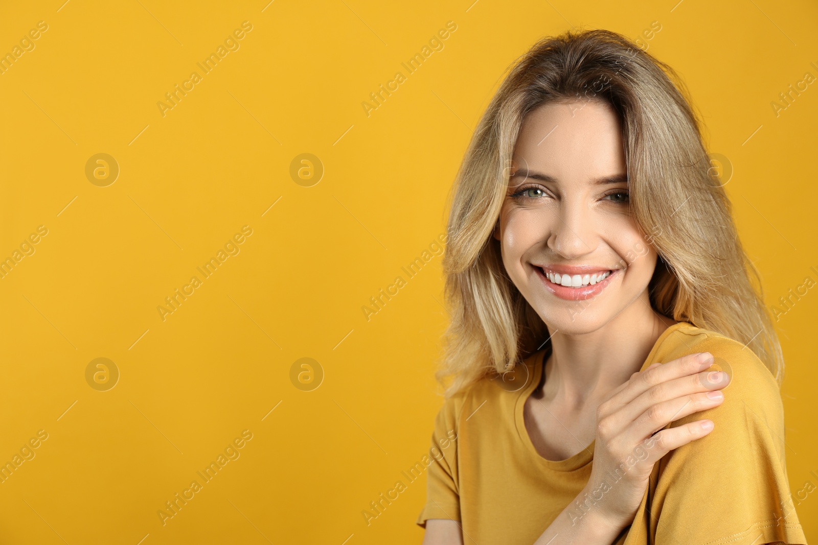 Photo of Portrait of happy young woman with beautiful blonde hair and charming smile on yellow background. Space for text