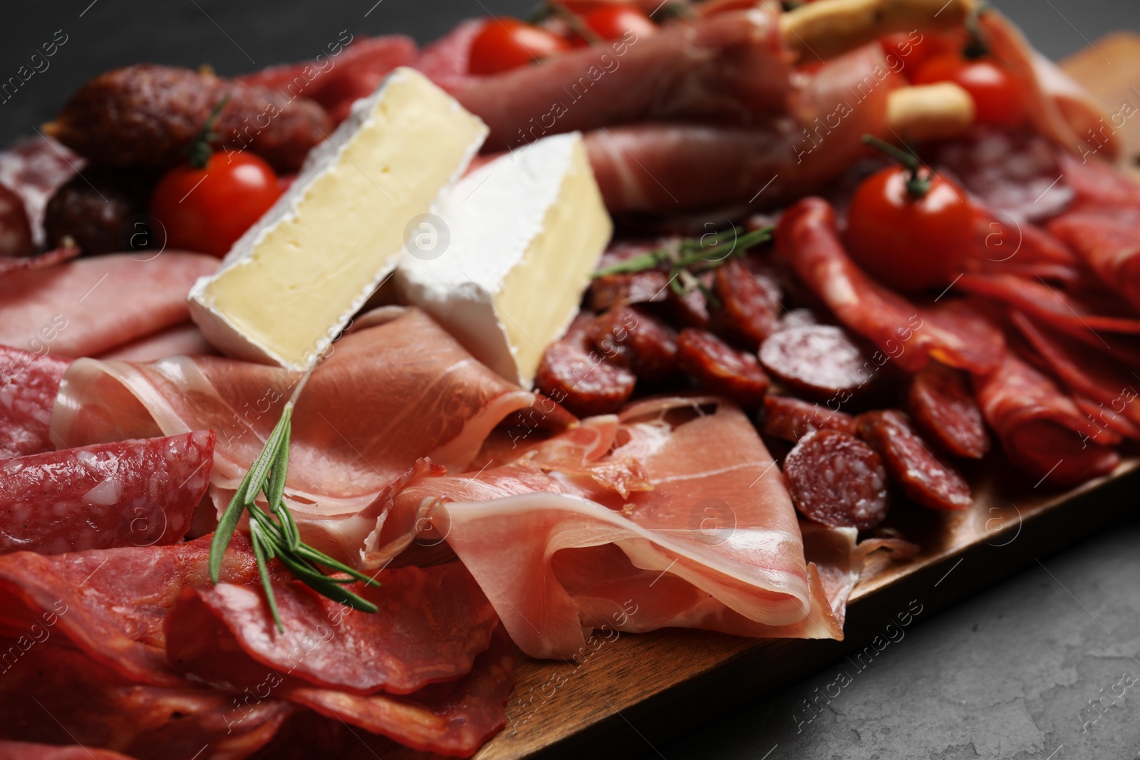 Photo of Tasty ham with other delicacies served on black table, closeup