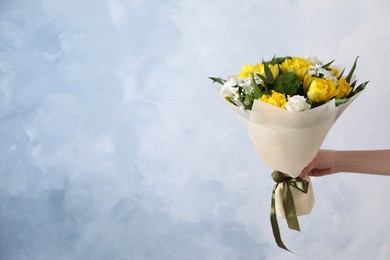 Photo of Woman with bouquet of beautiful tulips on light blue background, closeup. Space for text