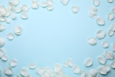 Photo of Beautiful white rose flower petals on light blue background, flat lay. Space for text