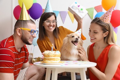 Happy friends celebrating their pet's birthday in decorated room