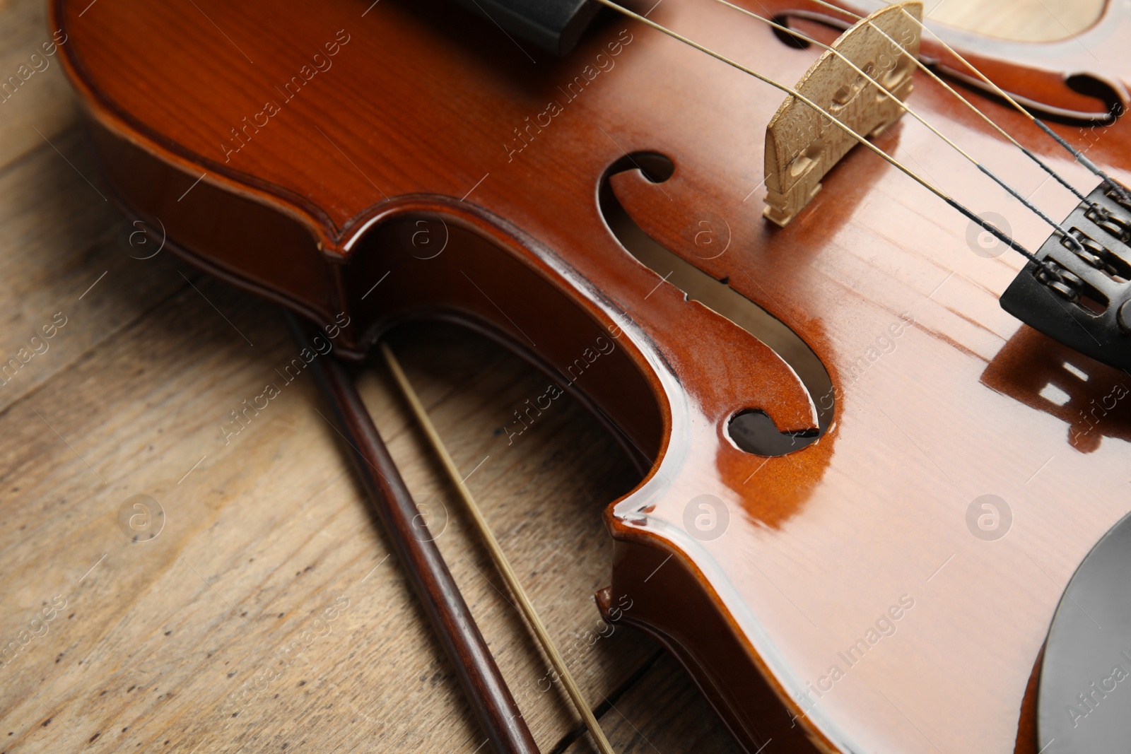 Photo of Beautiful violin and bow on wooden table, closeup