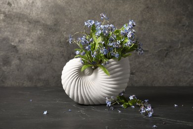 Photo of Bouquet of beautiful forget-me-not flowers in vase on gray textured table