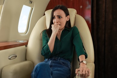 Photo of Nervous young woman suffering from aviophobia in airplane