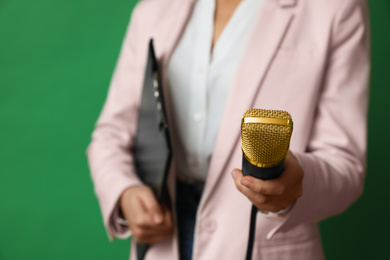 Photo of Journalist with microphone and clipboard on green background, closeup