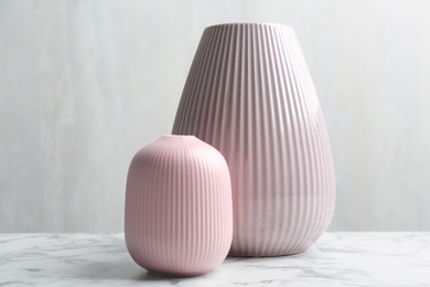 Stylish pink ceramic vases on white marble table