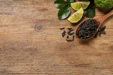 Photo of Dry bergamot tea leaves and fresh fruits on wooden table, flat lay. Space for text
