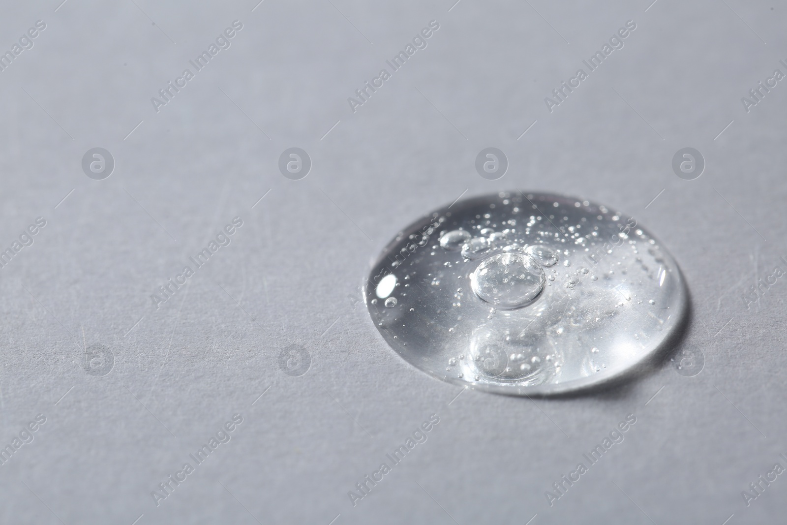 Photo of Drop of cosmetic serum on light background, macro view. Space for text