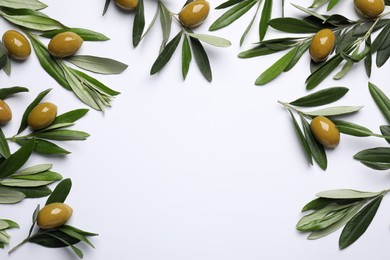 Twigs with olives and fresh green leaves on white background, flat lay. Space for text