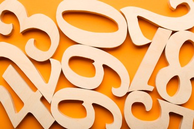Photo of Wooden numbers on orange background, flat lay