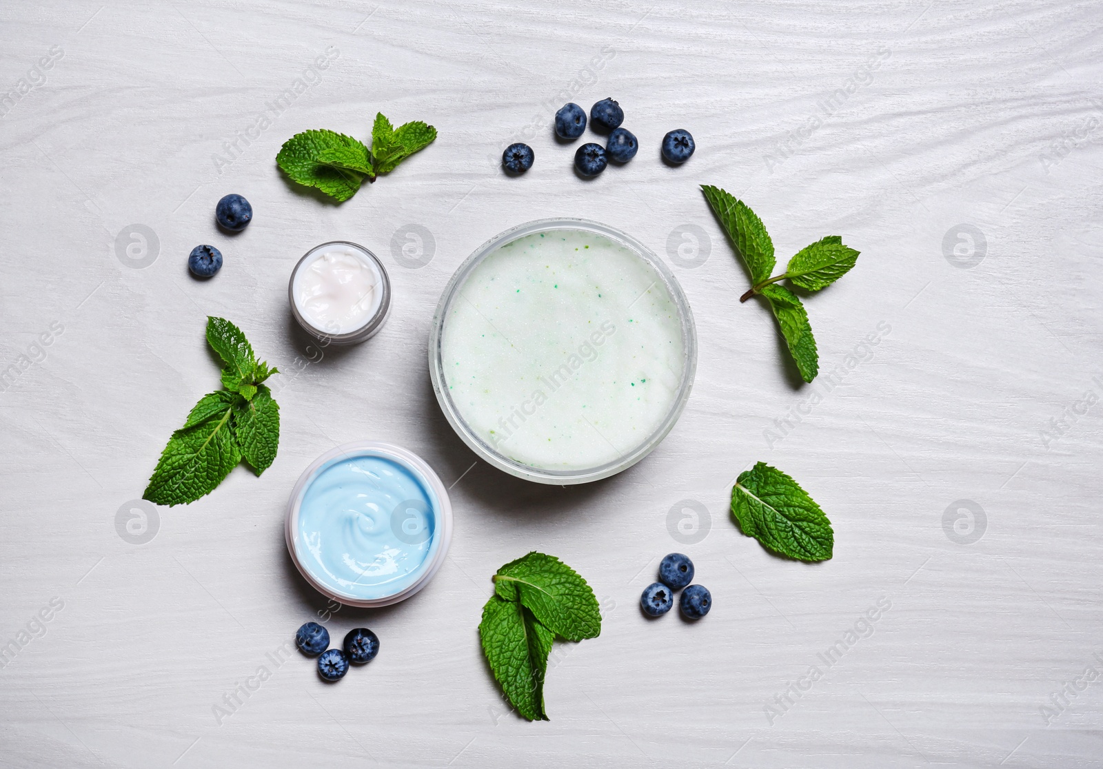 Photo of Flat lay composition with jars of body cream on light wooden background