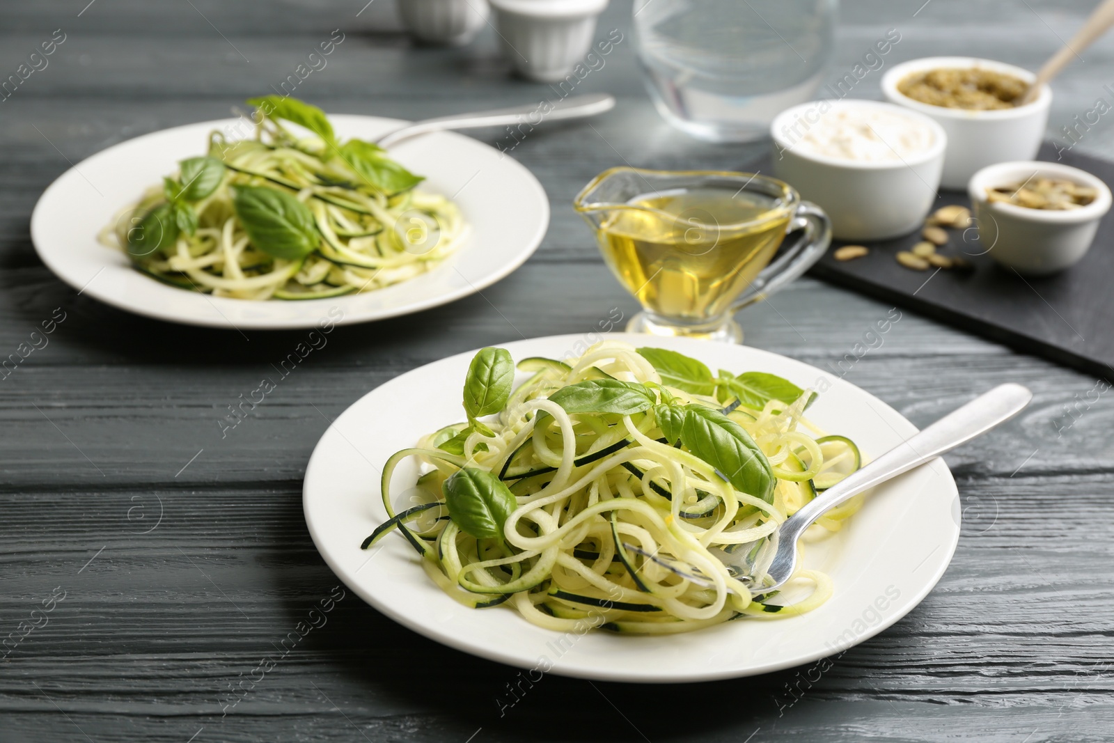 Photo of Delicious zucchini pasta with basil served on grey wooden table