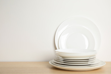Photo of Set of clean plates on wooden table against white background. Space for text