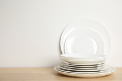 Set of clean plates on wooden table against white background. Space for text